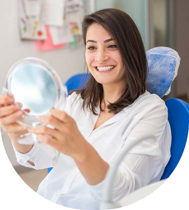 Woman looking in the mirror and smiling after checkup at dentist office stock image